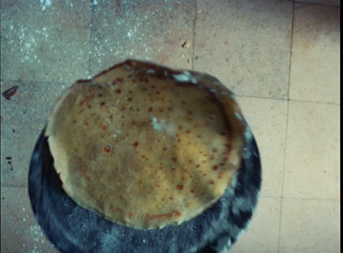 a pie sitting on top of a black plate on a tiled floor