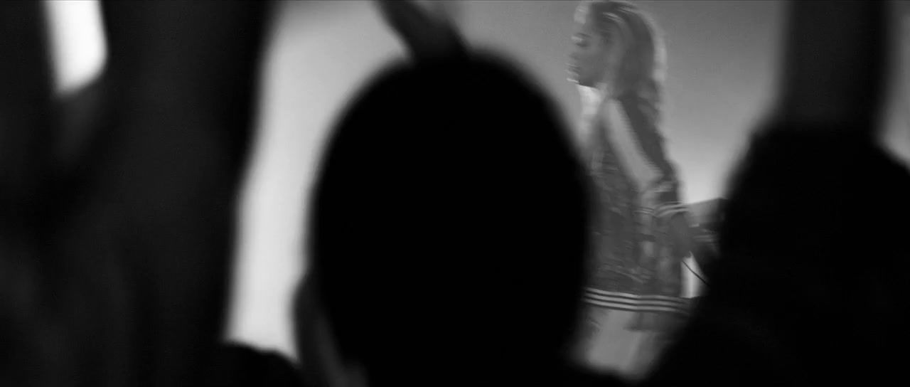 a black and white photo of a woman standing in front of a crowd