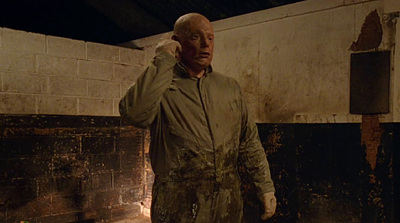 a man standing in a dirty room with a cell phone to his ear