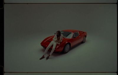 a woman sitting on top of a red sports car