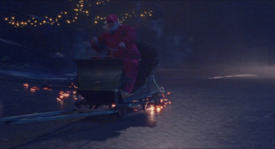 a man in a red suit riding on a sleigh