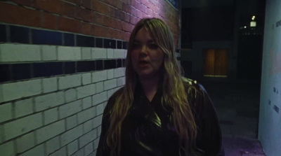 a woman standing in front of a brick wall