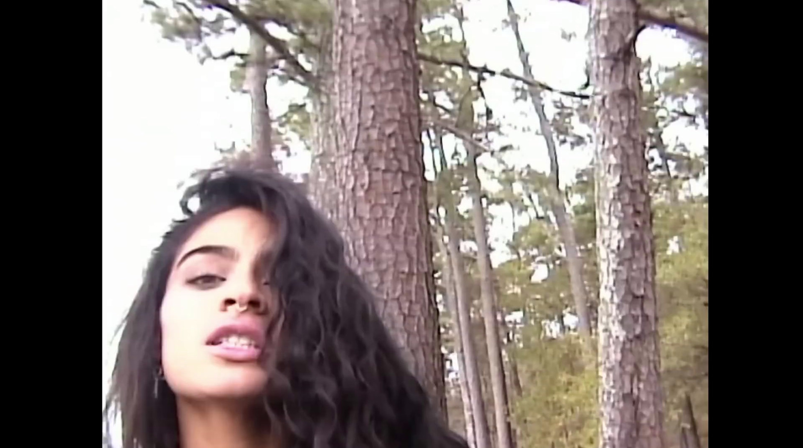 a woman with long hair standing in a forest