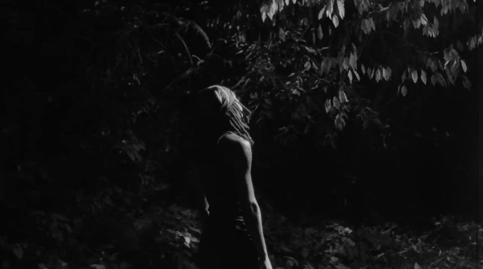 a woman standing in front of a tree in a black and white photo