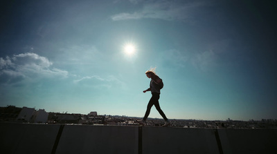 a woman walking across a bridge under a blue sky