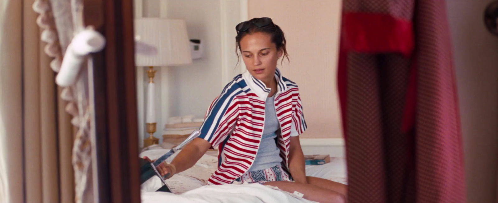 a woman in a red, white and blue shirt sitting on a bed