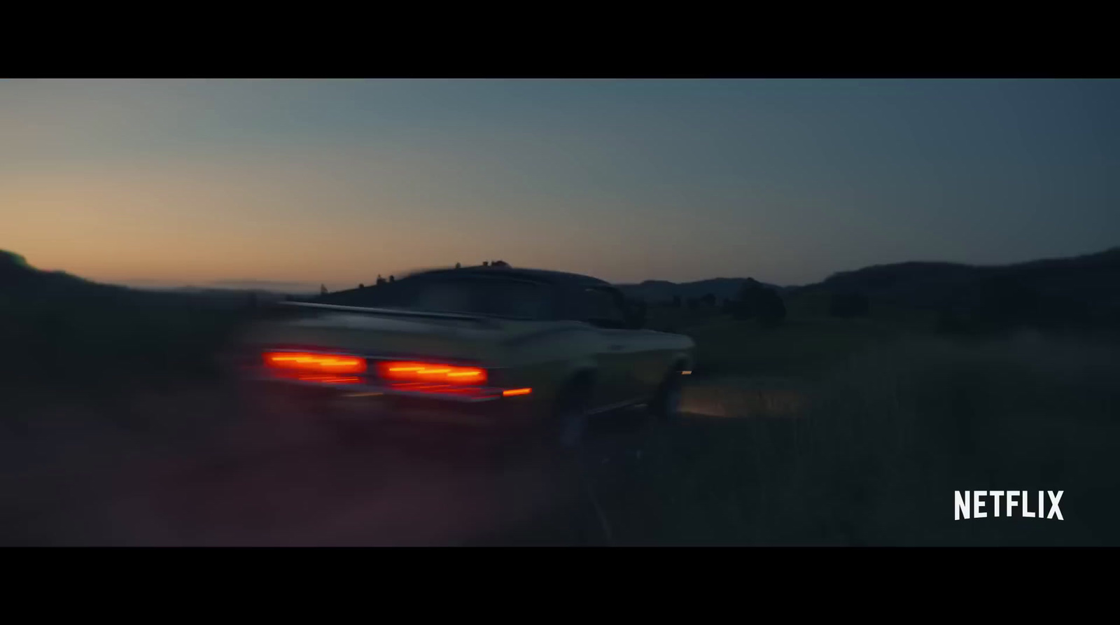 a car driving down a road at dusk