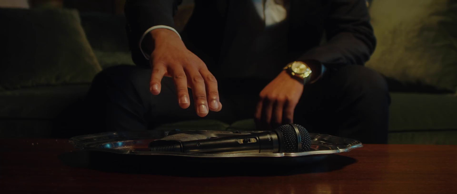 a man in a suit sitting on a couch with his hands on a remote control