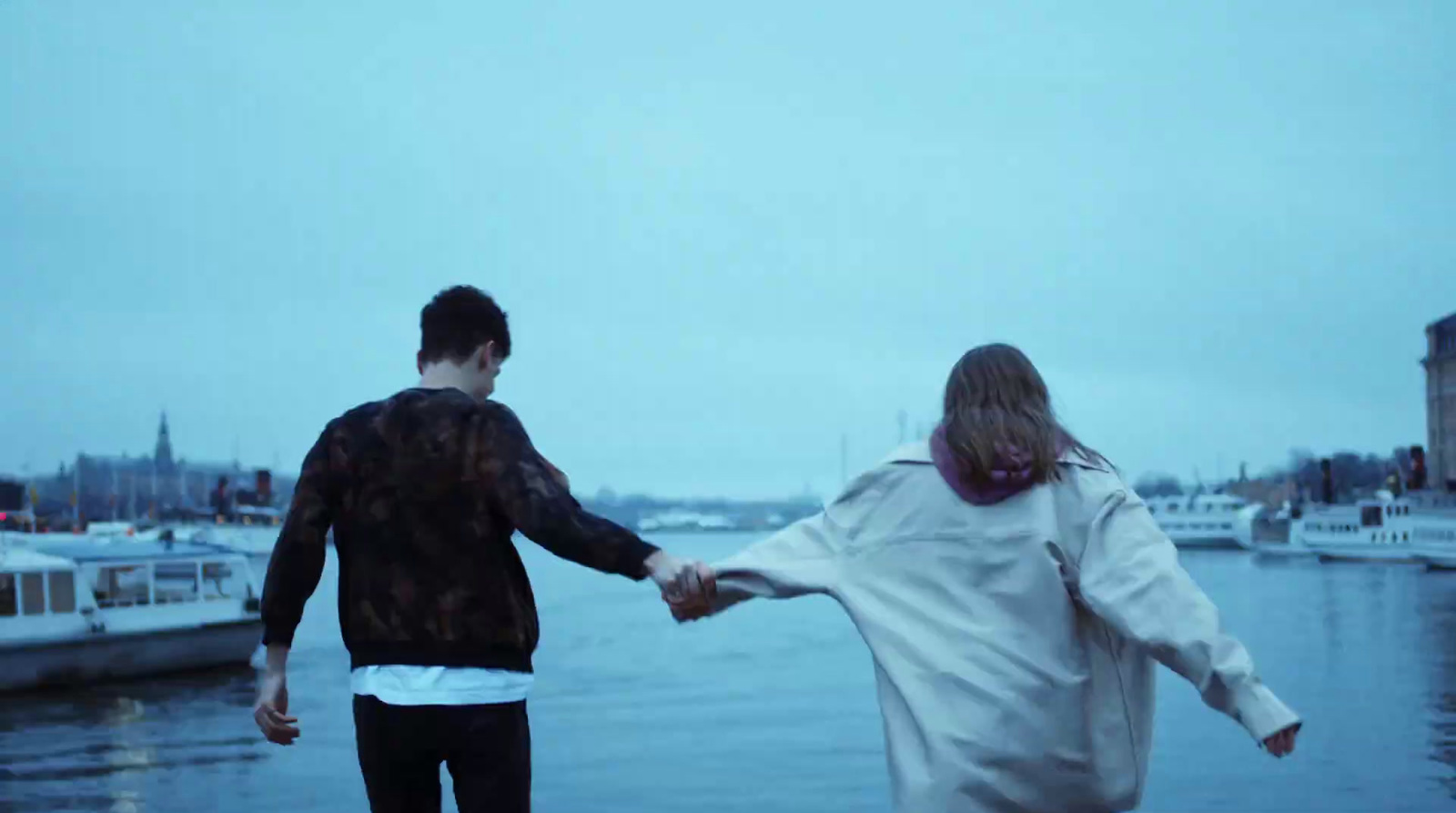 a man and a woman holding hands near a body of water