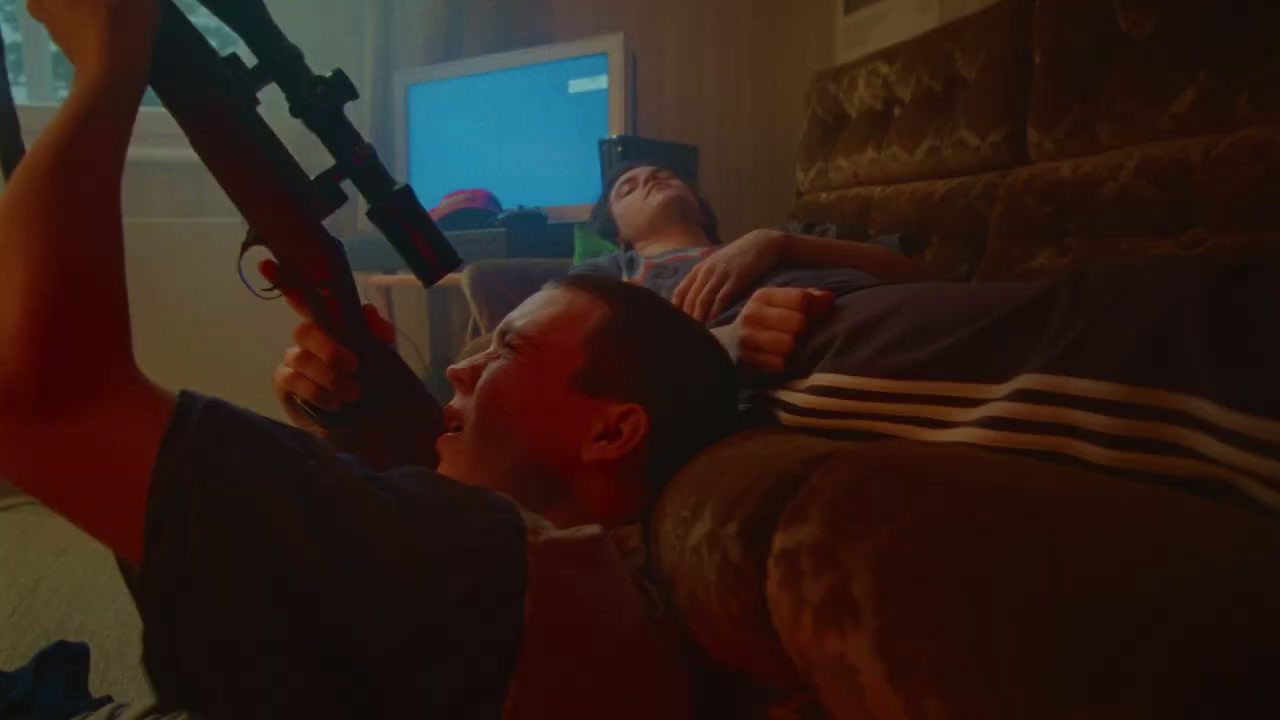 a man laying on a couch holding a gun