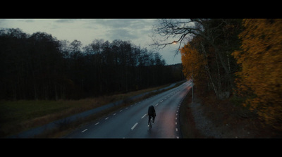 a man riding a bike down a road next to a forest