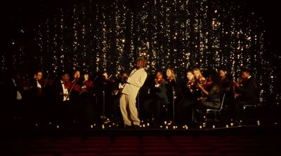 a man in a white suit standing on a stage