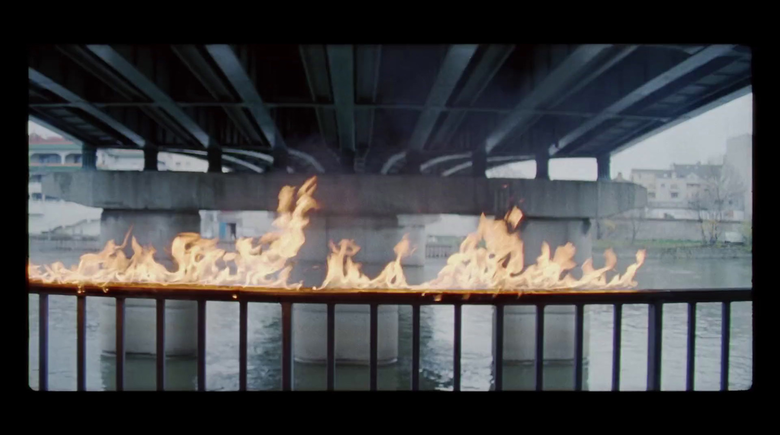 a fire is burning under a bridge over water