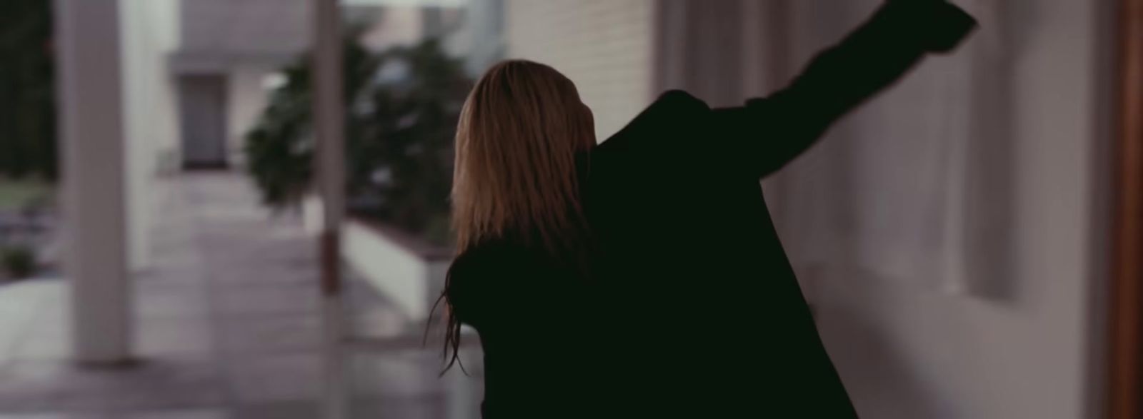 a woman standing in front of a window with her arms in the air