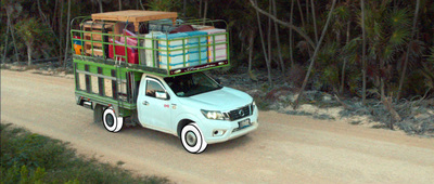 a truck with luggage on the back driving down a dirt road