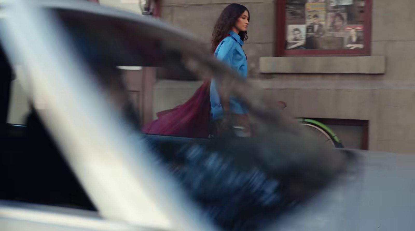 a woman walking down a street next to a car