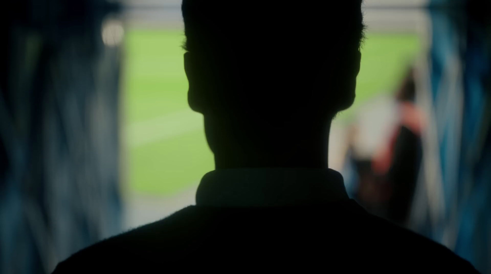 a silhouette of a man standing in front of a soccer field