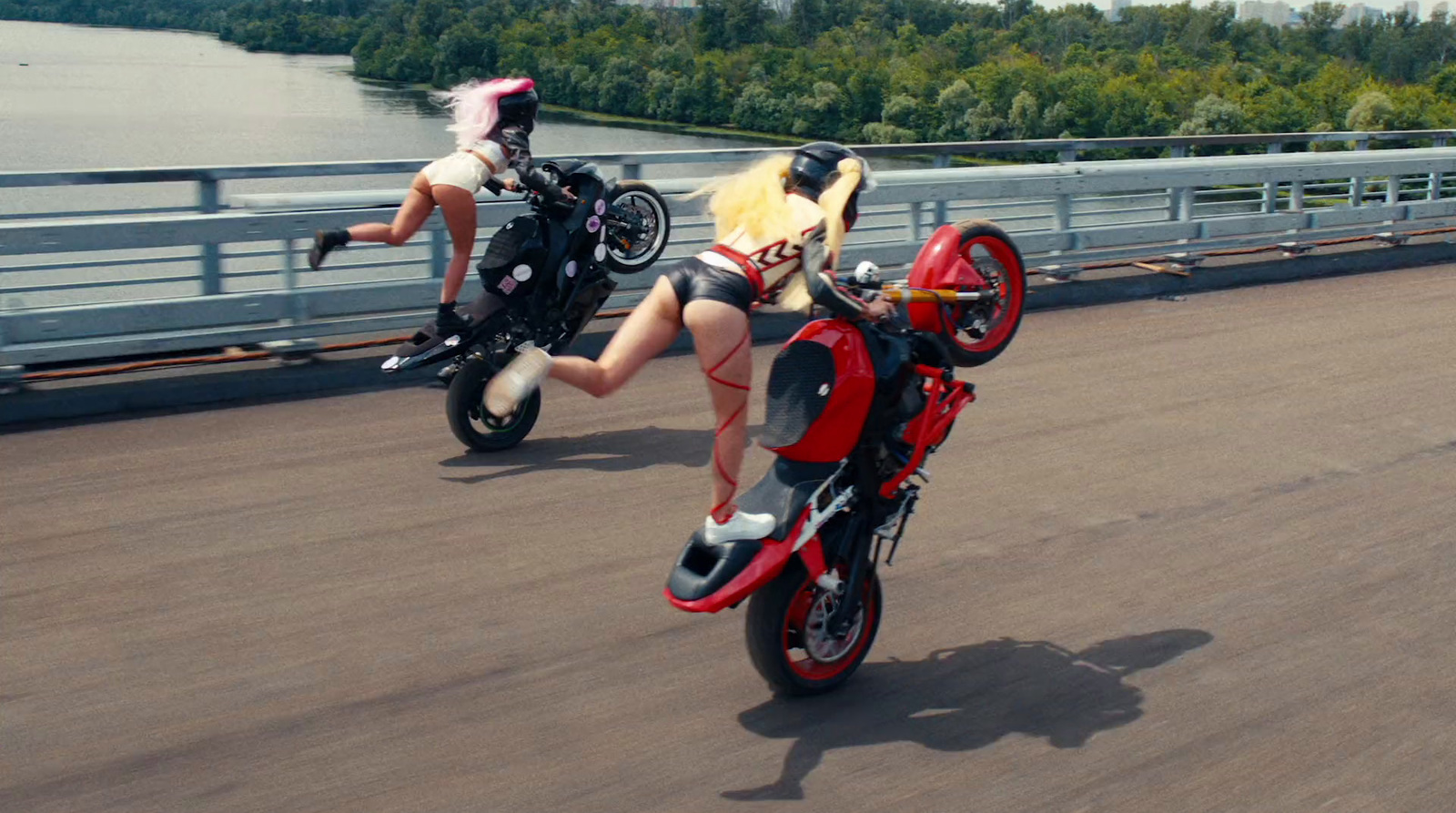 two women are riding motorcycles on a bridge