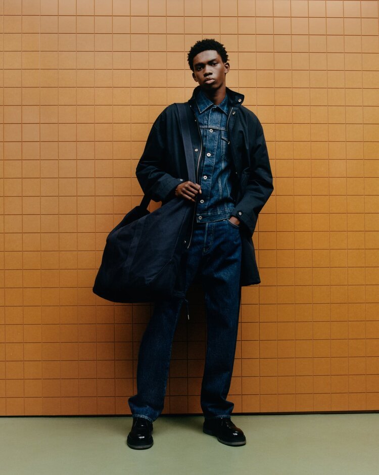 a man standing in front of a wall holding a bag