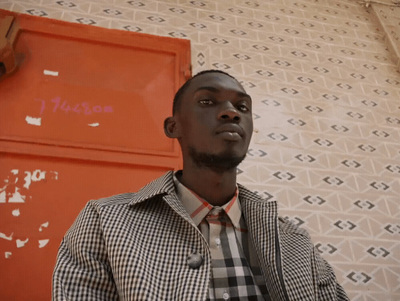 a man in a checkered shirt and tie standing in front of a red door