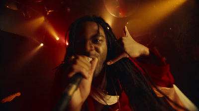 a man with dreadlocks is singing into a microphone