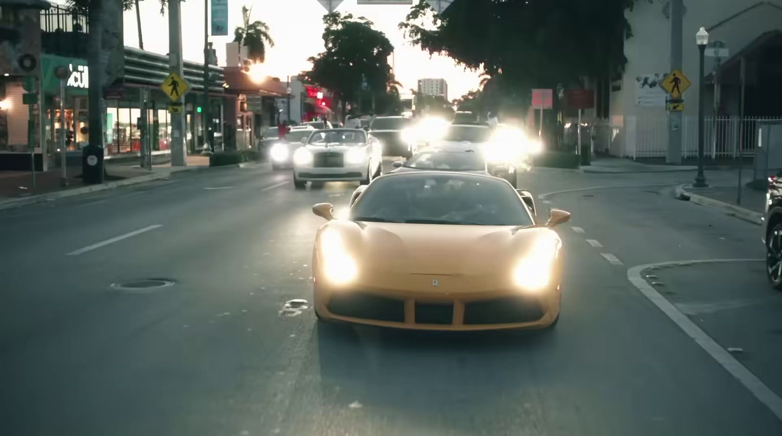 a yellow sports car driving down a street at night