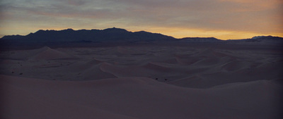 the sun is setting over the mountains in the desert