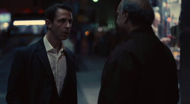 two men talking on a city street at night