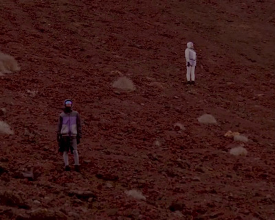 a couple of people standing on top of a dirt field