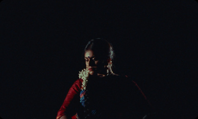 a woman standing in the dark with a flower in her hair