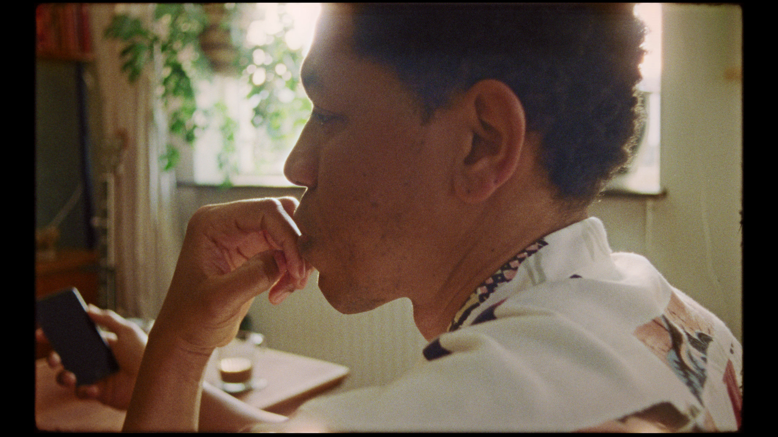 a man sitting at a table with a cell phone in his hand