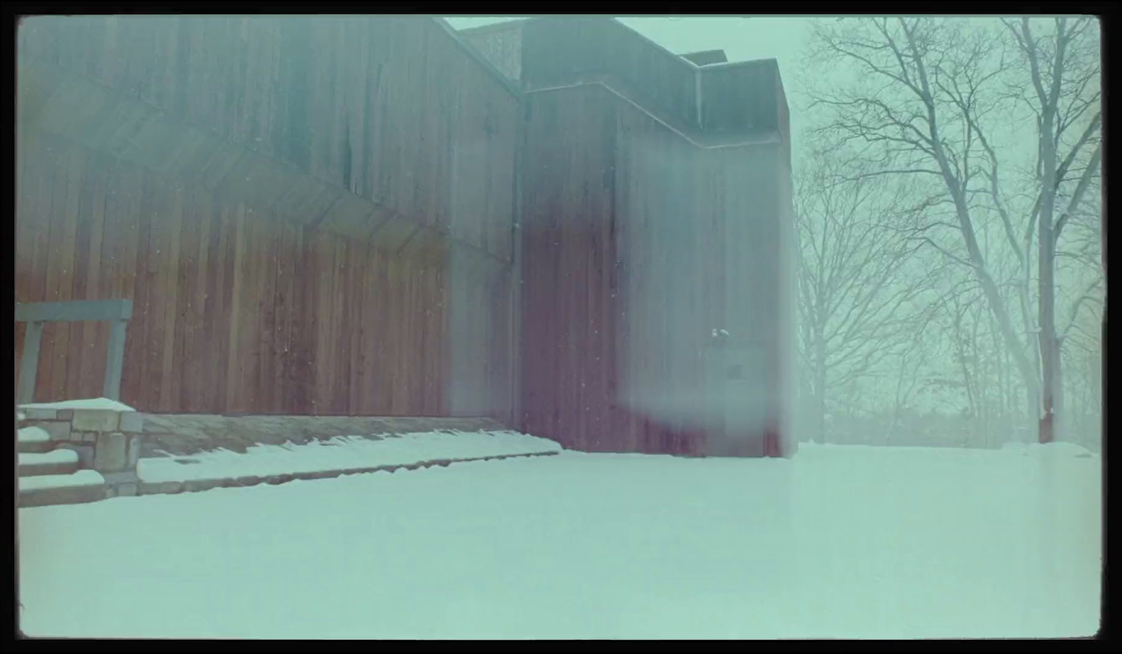 a barn in the snow with a bench in front of it