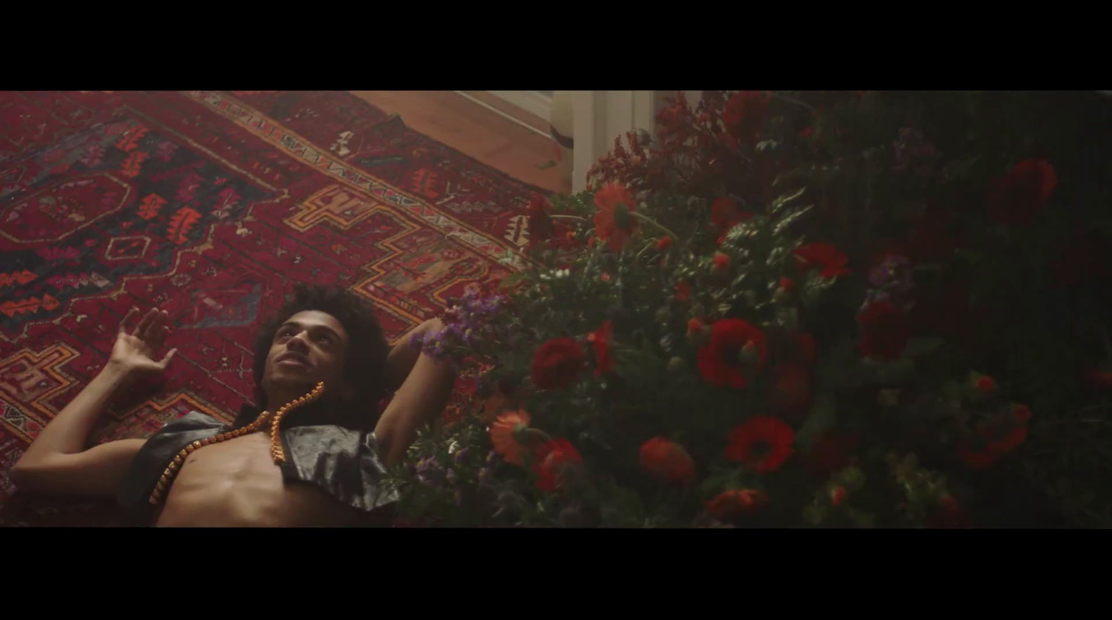 a man laying on a rug next to flowers