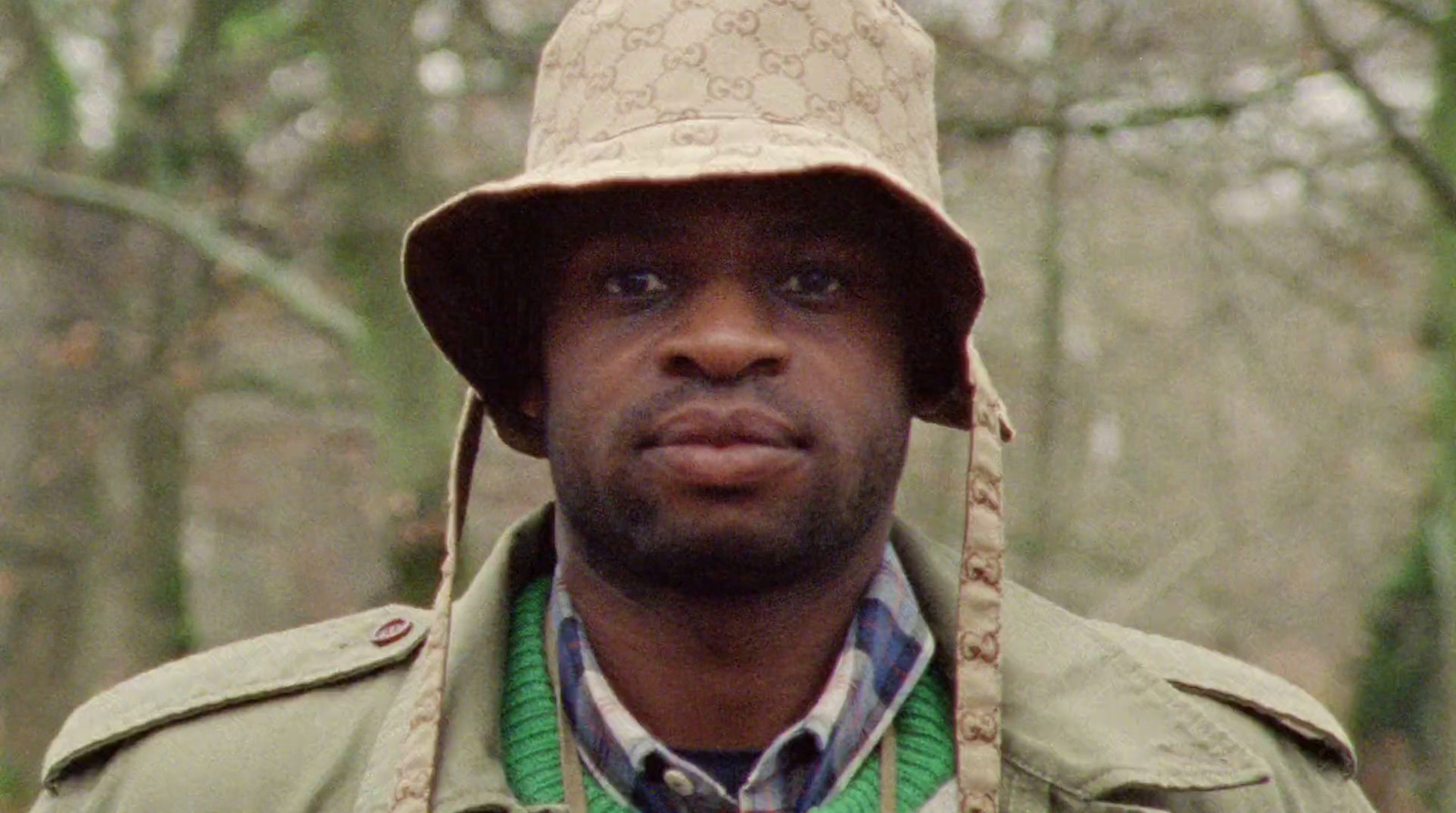 a man wearing a hat and jacket in the woods