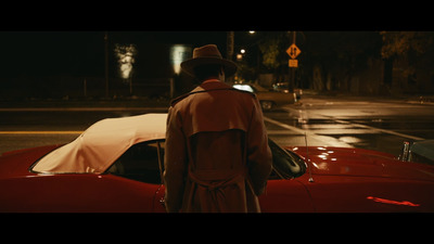 a man standing next to a red car at night