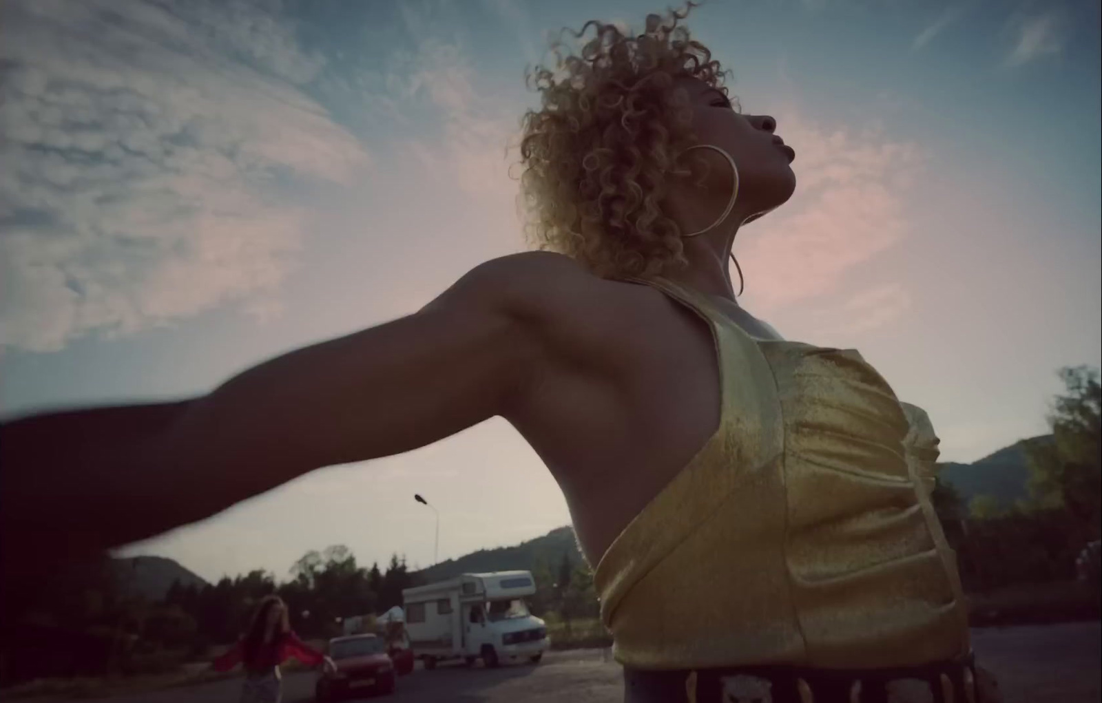 a woman in a yellow top standing in a parking lot