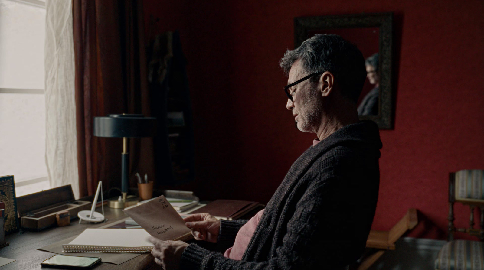 a man sitting at a desk holding a piece of paper