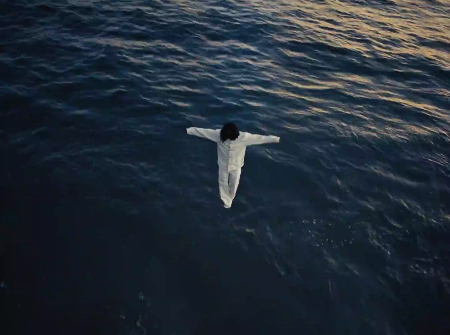 a man floating in the ocean with his arms outstretched