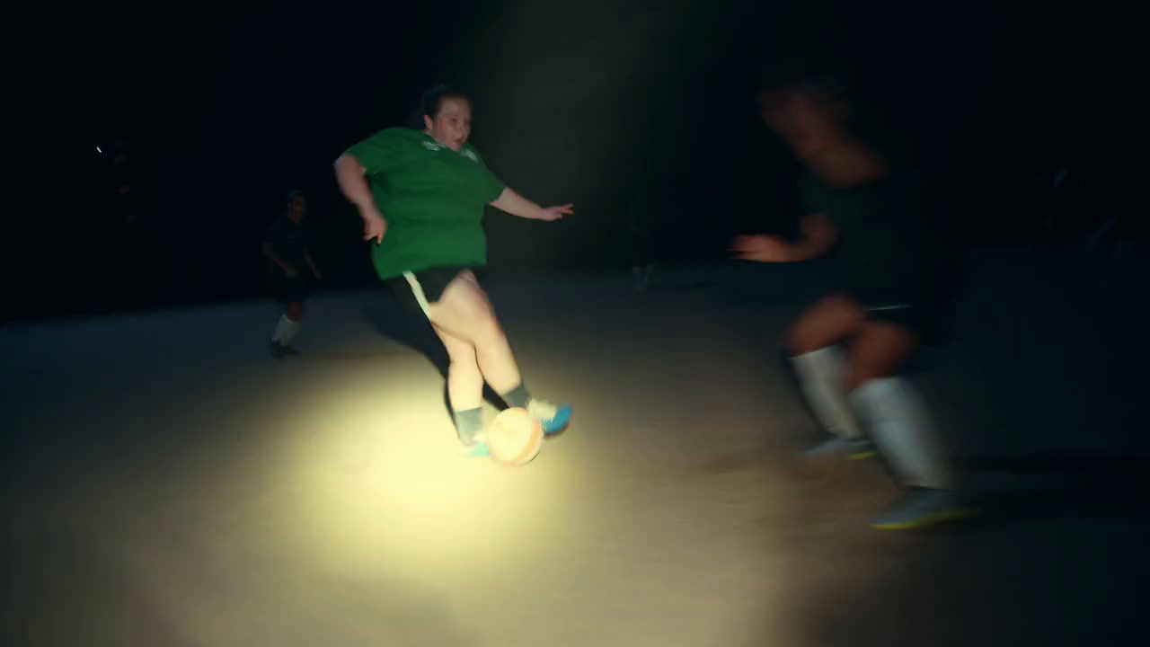 a man in a green shirt kicking a soccer ball