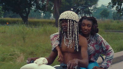 a man and woman riding a motorcycle down a street