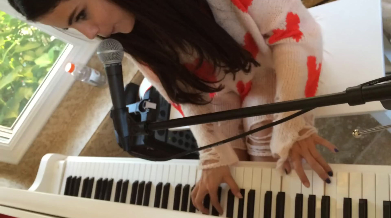 a woman playing a piano with a microphone