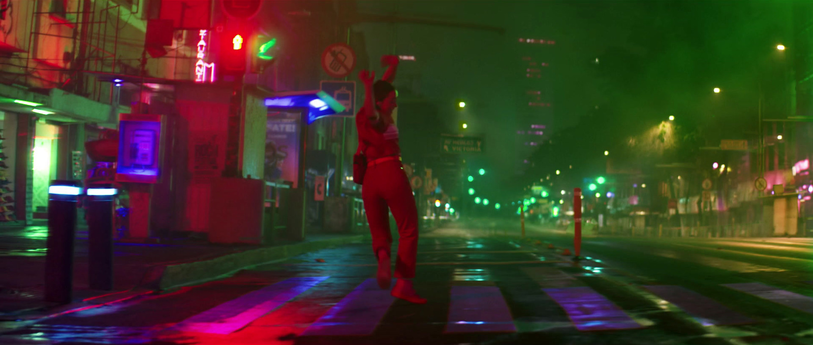 a woman standing on a crosswalk in the middle of a city at night