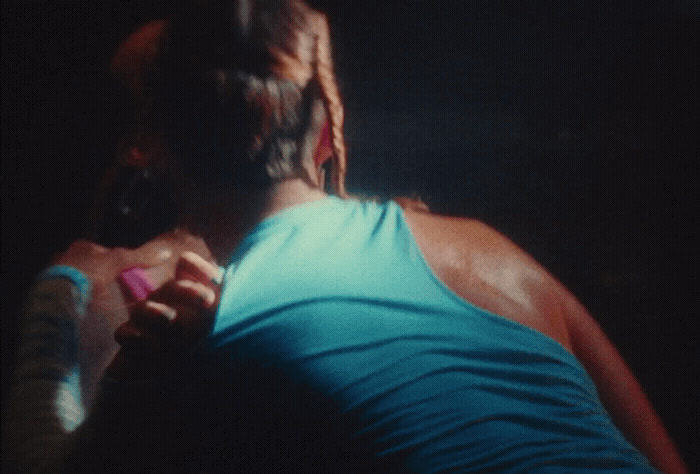 a man in a blue tank top holding a cell phone