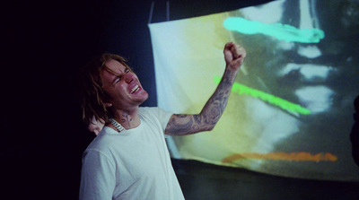 a man in a white t - shirt is pointing at a screen