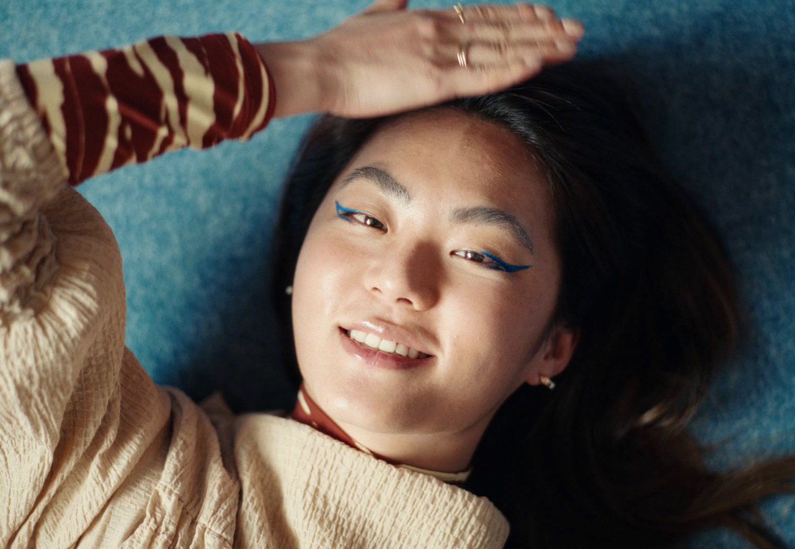 a woman laying on a blue carpet with her hands on her head