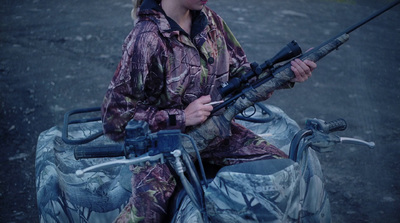 a woman sitting on top of a motorcycle holding a rifle