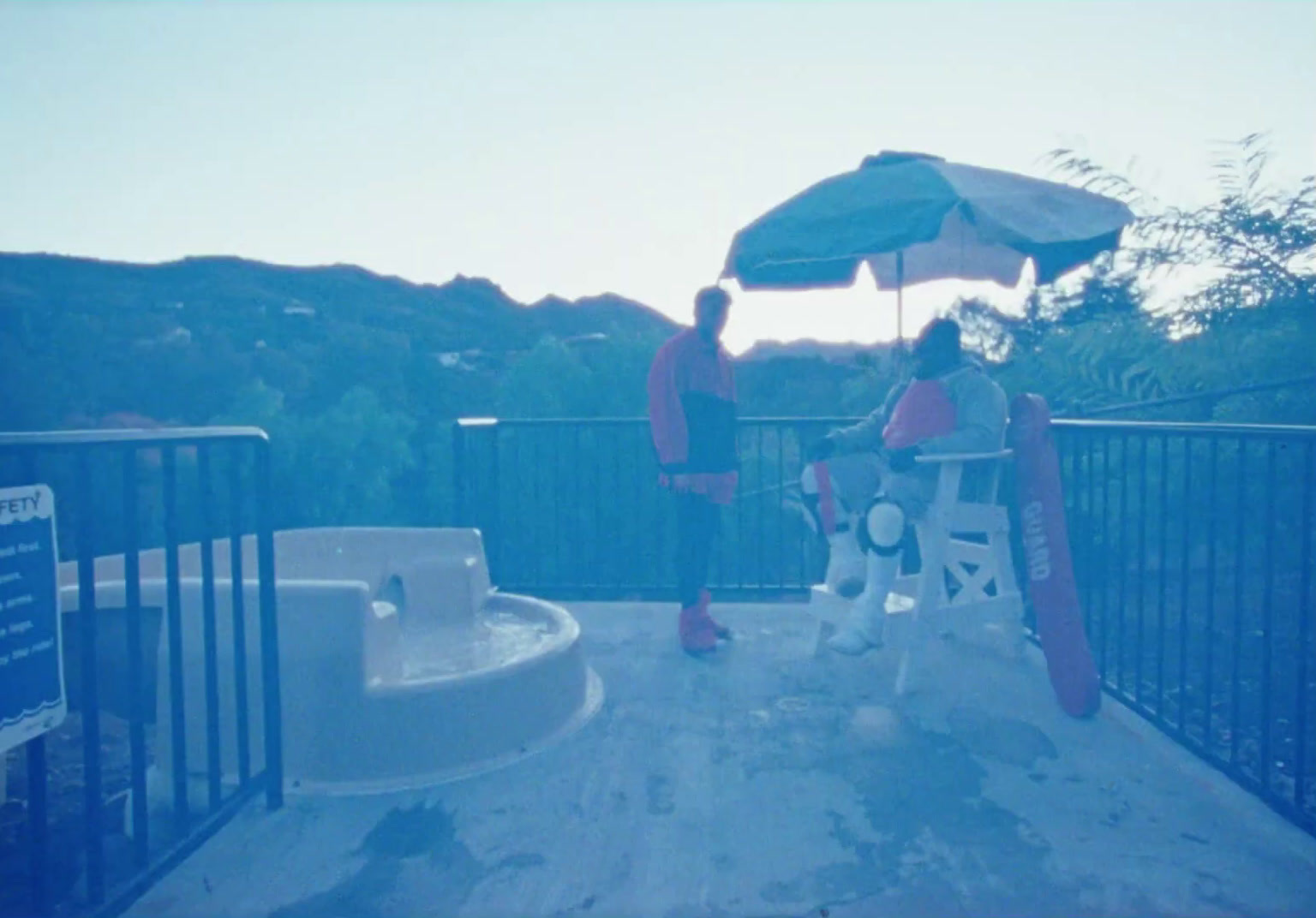 two people sitting under an umbrella on a deck