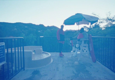 two people sitting under an umbrella on a deck