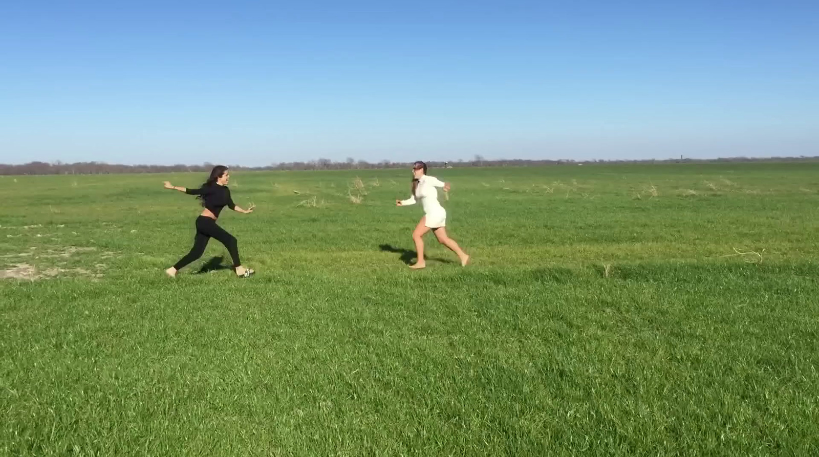 a couple of people running across a lush green field