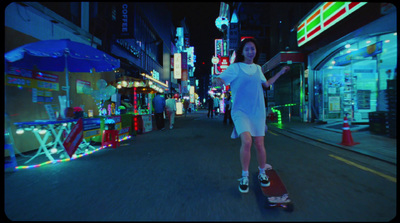 a woman riding a skateboard down a street at night